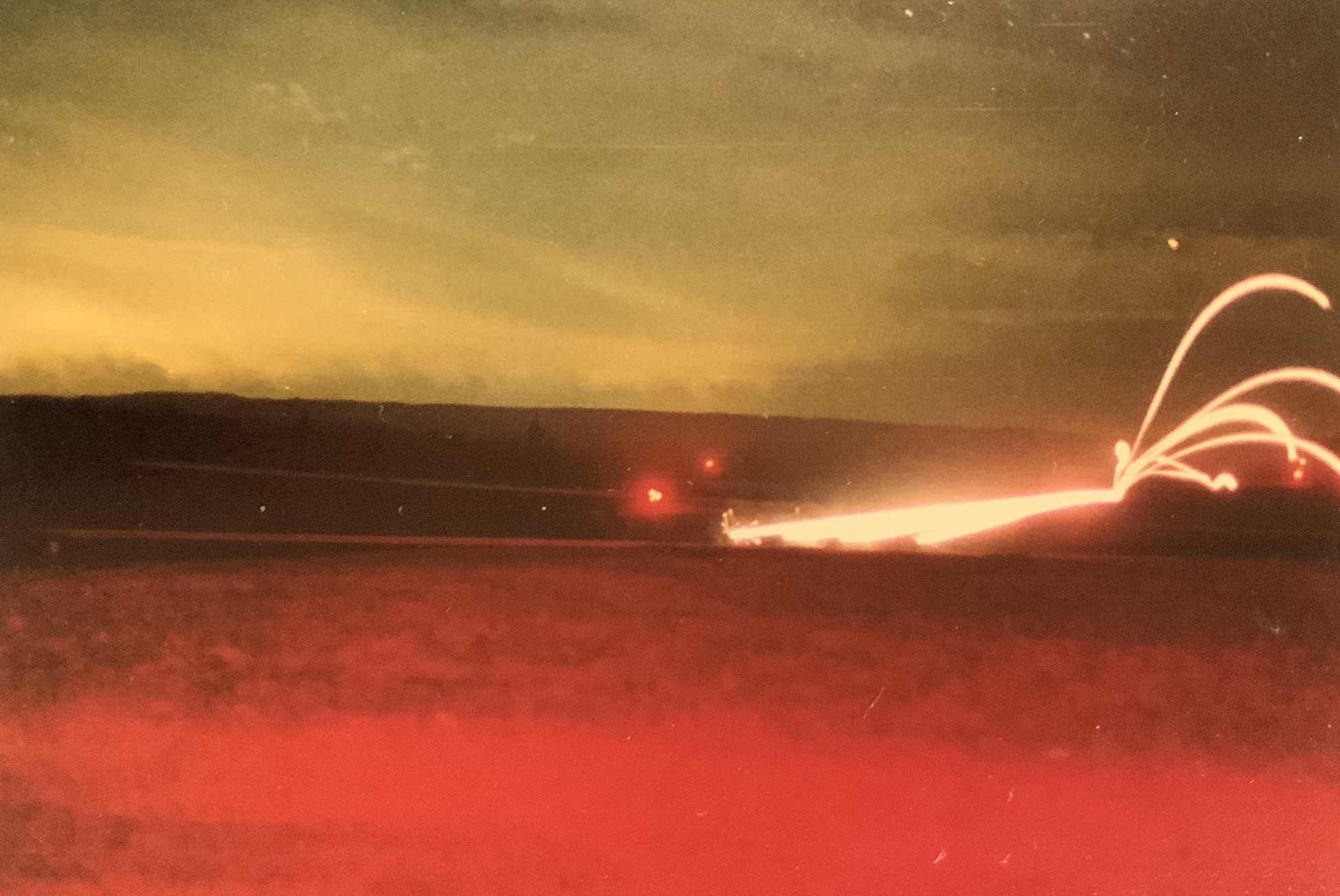 This is one of my photos from gunnery in May 1988. This is an M3 Bradley Fighting Vehicle firing on the move on range 397 at Granenwoehr. You can see the large lights off in the distance, which were range fan markers. These giant chevrons pointed in toward the center of the range. They were heated to show up on thermal night sights and gave crews a reference to stay oriented and keep their weapons pointing at the correct target area. The red glow in the bottom of the picture was from the lights inside the range control tower, which I was standing in front of.